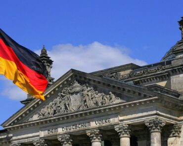 The German Flag in front of the Reichstag building in Berlin; Credits: Wikipedia