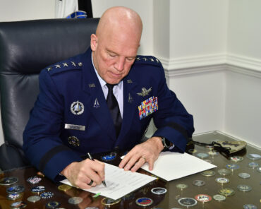 Chief of Space Operations Gen. John W. Raymond signs a memorandum of understanding in his office at the Pentagon with the Japanese government, allowing Space Force to put hosted payloads on the Quasi-Zenith Satellite System, Arlington, Va., Dec. 15, 2020. The QZSS was developed by the Japan to enhance American GPS in the Asia-Pacific region. (U.S. Air Force photo by Eric Dietrich)