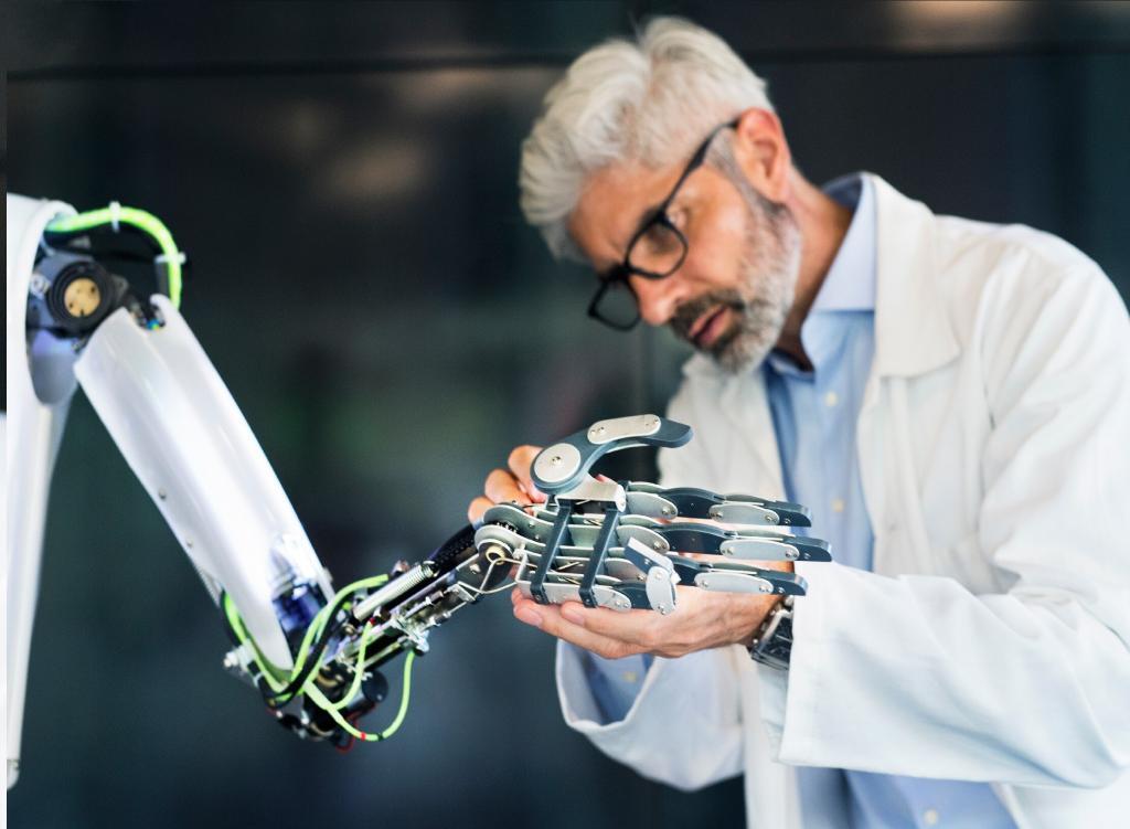 Mature businessman or a scientist with gray hair with a robot. Credit Space Foundation