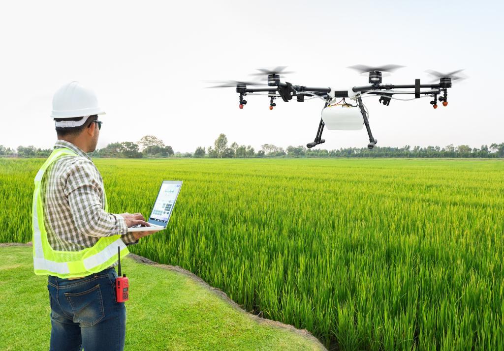 Technician farmer use wifi computer control agriculture drone fly to sprayed fertilizer on the rice fields, Smart farm 4.0 concept. Credit Space Foundation