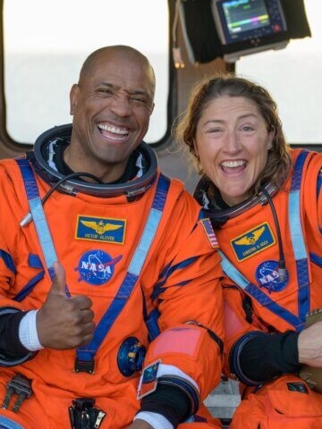 NASA astronaut Victor Glover, Artemis II pilot, left, and NASA astronaut Christina Koch, Artemis II mission specialist are seen sitting on a Navy MH-60 Seahawk from Helicopter Sea Combat Squadron (HSC) 23 on the flight deck of USS John P. Murtha after they and fellow crewmates CSA (Canadian Space Agency) astronaut Jeremy Hansen, Artemis II mission specialist, and NASA astronaut Reid Wiseman, Artemis II commander, were extracted from their Orion spacecraft after splashdown, Friday, April 10, 2026, in the Pacific Ocean off the coast of California. NASA’s Artemis II mission took the quartet on a nearly 10-day journey around the Moon and back to Earth. Following a splashdown at 5:07 p.m. PDT (8:07 p.m. EDT), NASA, U.S. Navy, and U.S. Air Force teams are working to bring the Orion spacecraft aboard the recovery ship. Photo Credit: (NASA/Bill Ingalls)